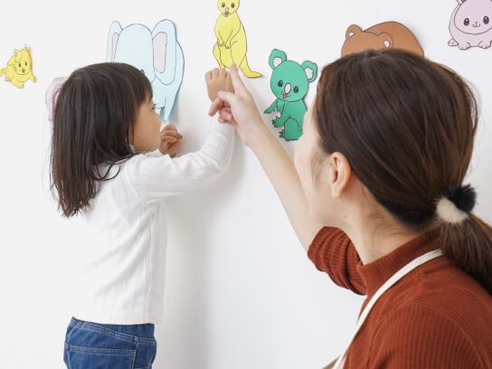 一時保育にて子供が壁に貼ってある動物の絵を指している写真